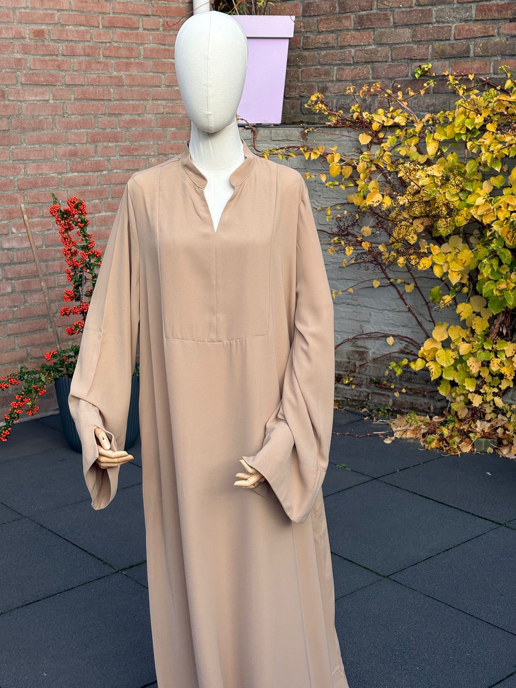 Abaya Sand — bandkraag met V-opening, wijde mouwen, maxi-lengte.