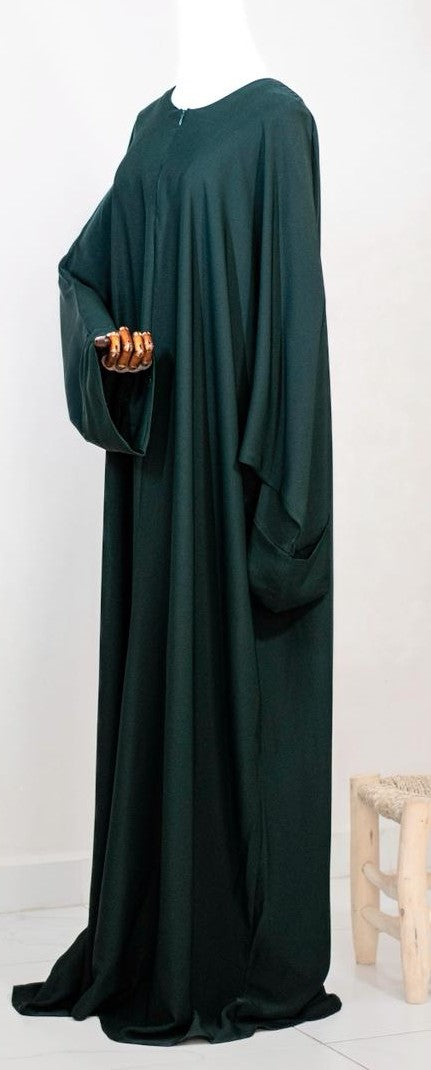 Abaya in midnight green van Saahil Collection, getoond op houten mannequin met wijdvallende mouwen en minimalistische achtergrond.